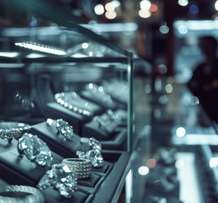 A Dimly Lit Jewelry Store Display. Rows Of Shimmering Lab-Grown Diamonds Rest Under Glass, Their Once Dazzling Brilliance Overshadowed By The Soft, Ambient Light. The Delicate Reflections Create A Moody Atmosphere, Hinting At The Market'S Decline. In The Background, A Blurred Figure, Perhaps A Jeweler, Stands With Crossed Arms, Embodying The Uncertainty Of The Industry. The Scene Exudes A Sense Of Quiet Tension And Impending Change From The Lab-Grown Diamond Market Slowdown